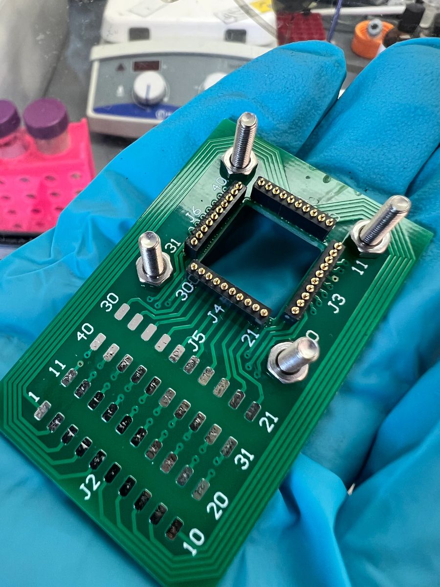 Neuroink engineer handling a custom chip carrier during applications testing